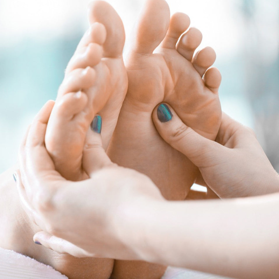 Two feet with thumbs massaging soles.