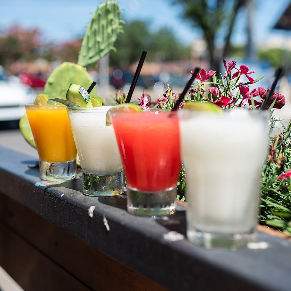 Four Cocktails lined up on a wall outside.