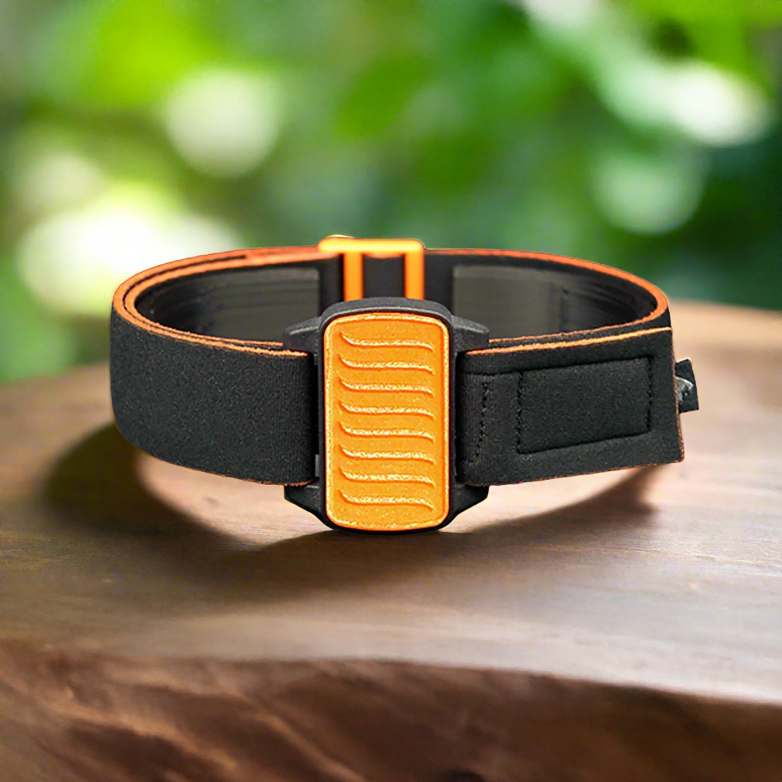 Dexband CGM armband with orange wave cover and neoprene strap, compatible with Dexcom G6 sensors, on wooden surface in outdoors setting.