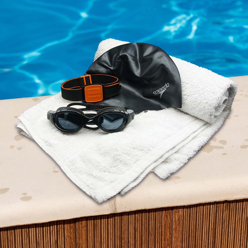 Swimming with a Libre sensor blog showing towel, swimming cap and Libreband for sensor protection on side of swimming pool.
