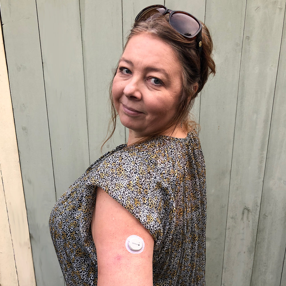 Woman showing Dexcom G7 cgm on upper arm.