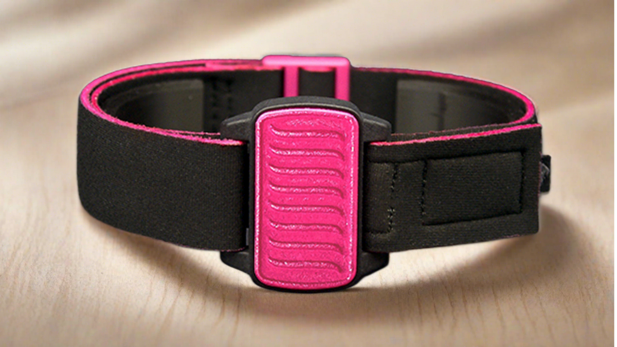 Dexband for G6 CGM on oak table, magenta cover with wave design and black strap.
