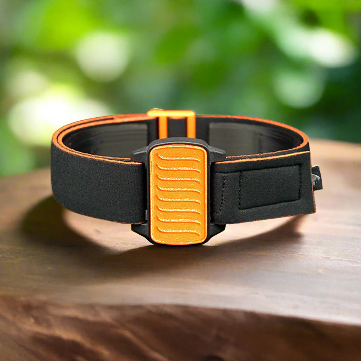 Dexband CGM armband with orange wave cover and neoprene strap, compatible with Dexcom G6 sensors, on wooden surface in outdoors setting.