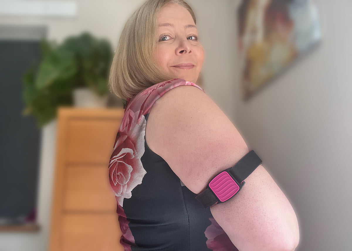 Model wearing Libreband armband in magenta with wave design on upper arm. Black strap edged in coordinating magenta.