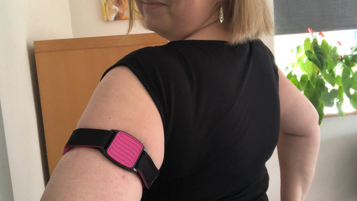 Model wearing Libreband armband cover in magenta with wave design on upper arm. Black strap edged in coordinating magenta