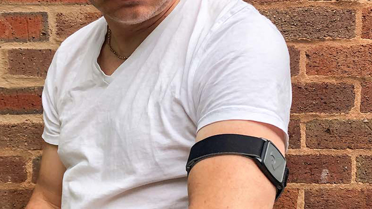 Model wearing Libreband armband cover in pewter with heart design. Black strap edged in coordinating pewter.