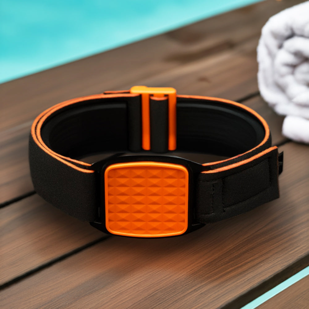 An orange and black Freestyle Libre 2 CGM sports armband with a pyramid design, placed on a wooden surface near a white towel.