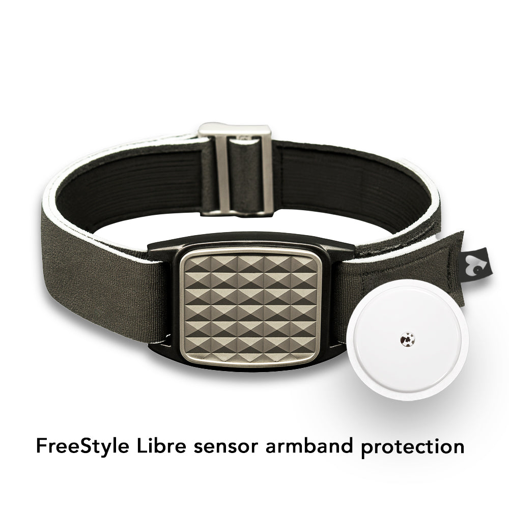 Black strap Libreband for FreeStyle Libre with silver pyramids style cover on a reflective surface with inset and pool in background.