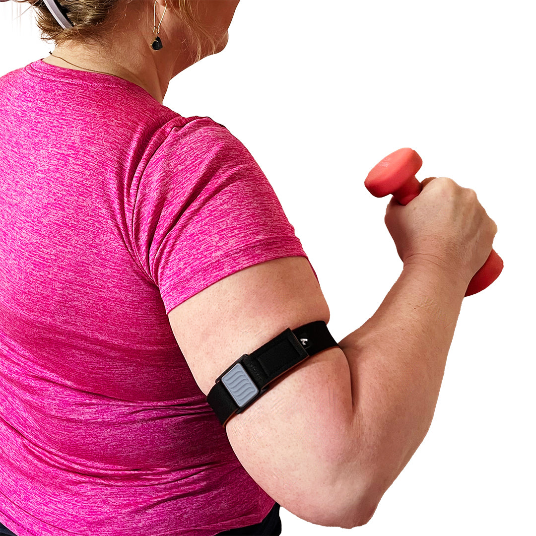 Libreband Armband for Freestyle Libre 3. Pewter cover with wave design. Shown on upper arm of woman exercising. LML4795, LML3828, LML3811, LML3804.