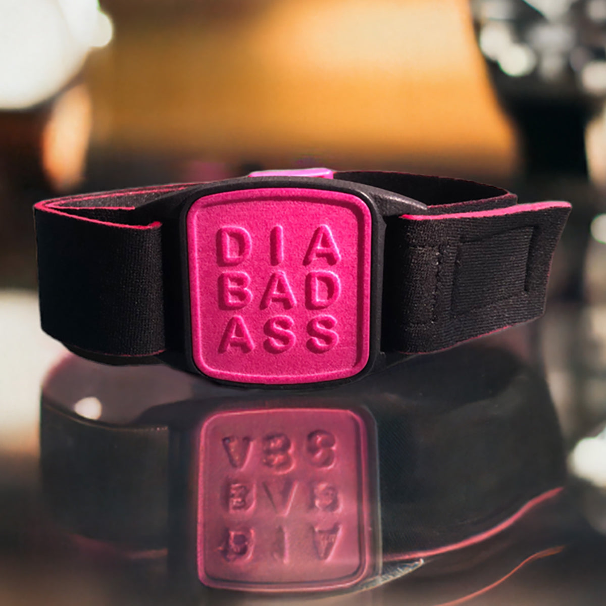 Libreband CGM armband for FreeStyle Libre 2 with magenta DIABADASS cover and black water-resistant neoprene strap on reflective glass surface. LML4108, LML4115, LML4122, LML4474.