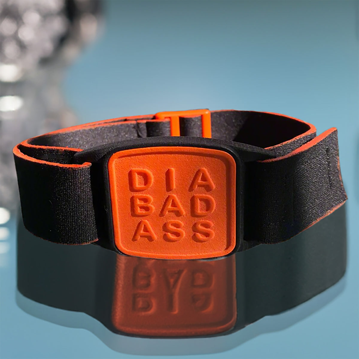 Dexband CGM armband with orange diabadass cover and neoprene strap, compatible with Dexcom G7 and ONE+ sensors alongside jewellery. LML4016, LML4023, LML4030, LML5006.