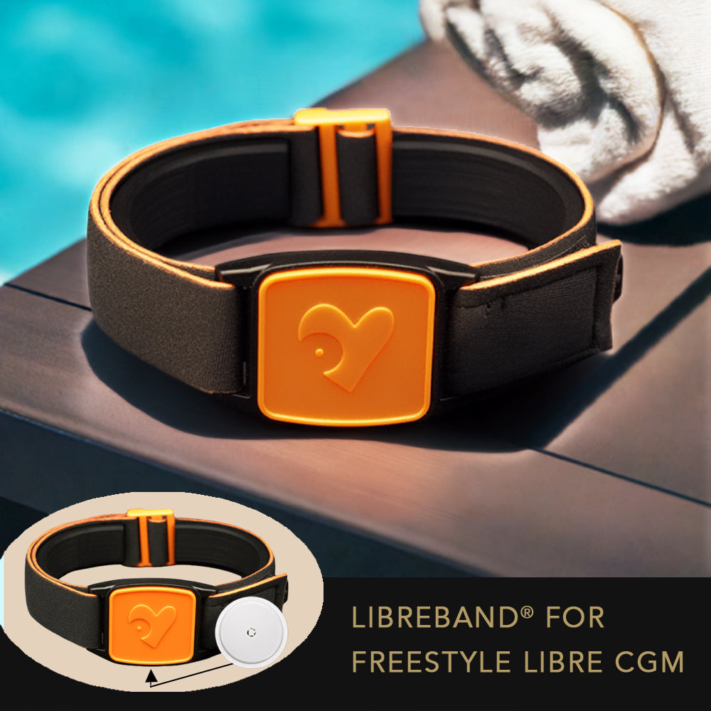 Black and orange Libreband armband for Freestyle Libre CGM on a dark wooden surface with pool background.